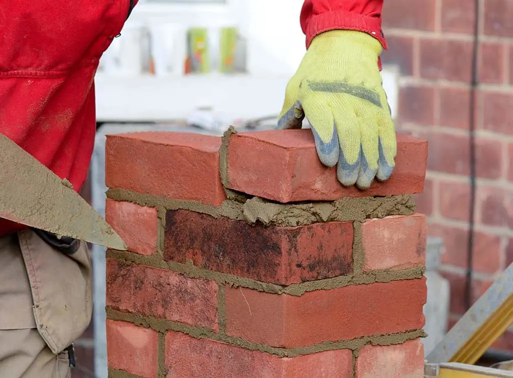 Skilled bricklayer repointing a period brick wall in Colchester